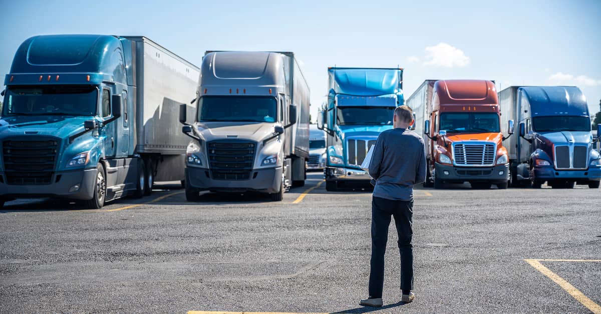 Inspector standing in front of a row of semi trucks. | Maggiano, DiGirolamo & Lizzi