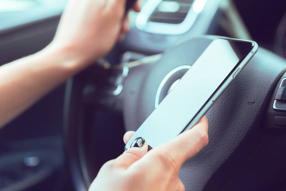 woman holding cell phone while driving