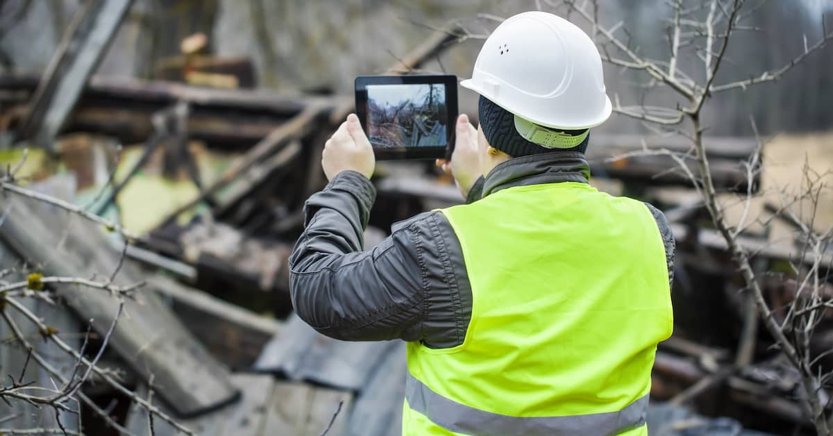 inspector with a tablet device surveying a collapsed structure