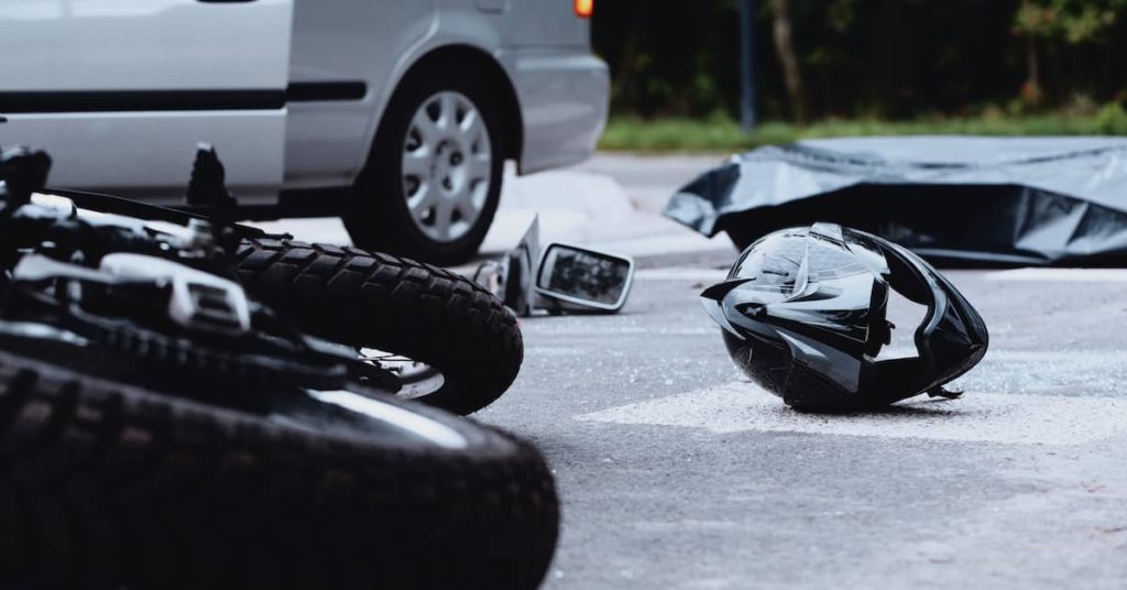 crashed motorcycle and helmet at the scene of an accident with a car