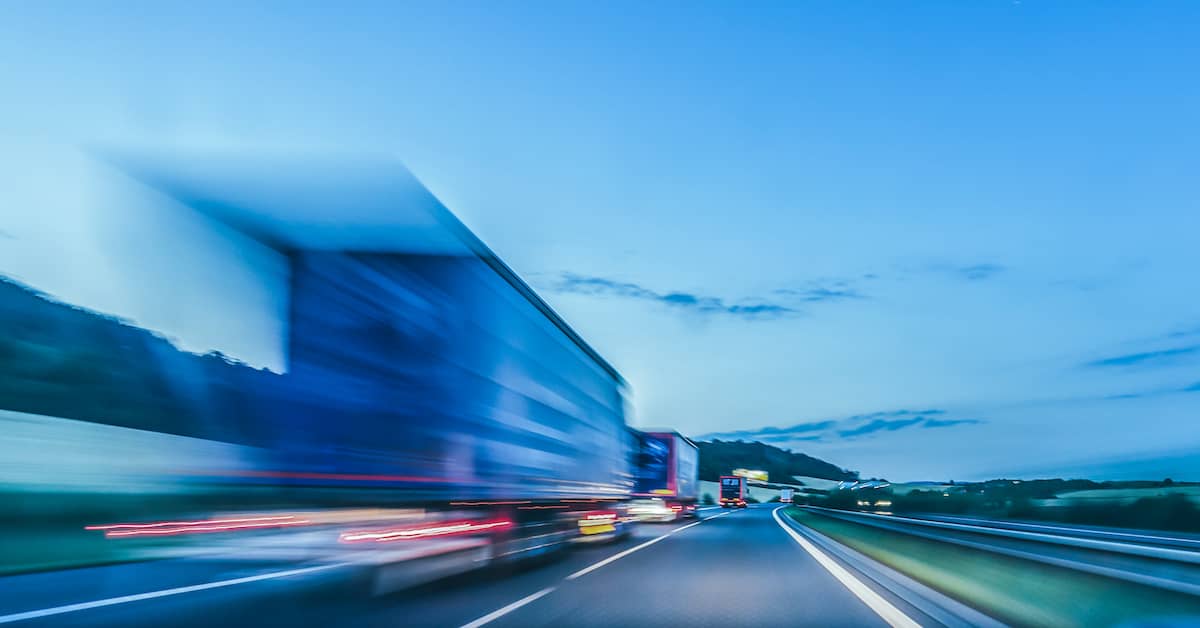 semi-trucks speeding on a highway at dusk