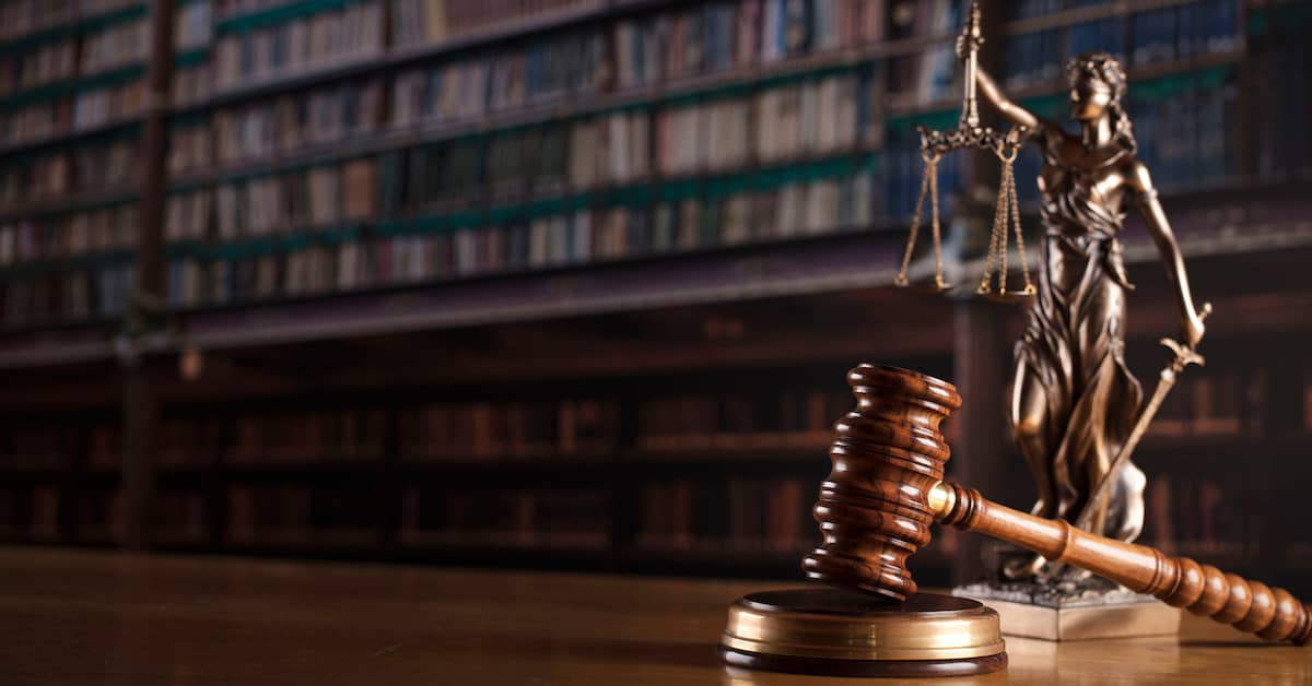 Lady Justice statuette standing next to gavel in library.