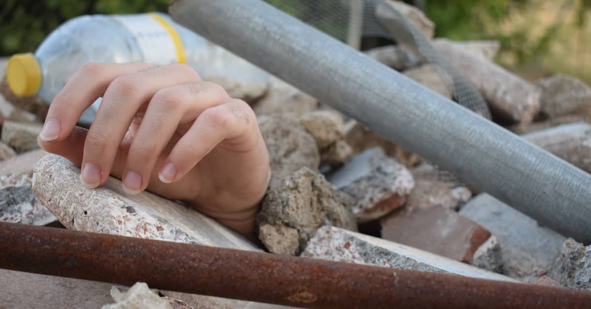 Hand sticks out of rubble after building collapse. | Maggiano, DiGirolamo & Lizzi