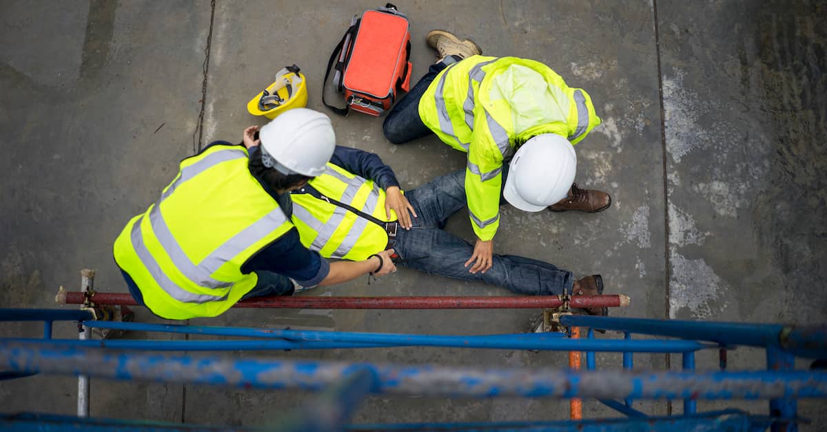 An injured construction worker is on the ground as two others tend to him. | Maggiano, DiGirolamo & Lizzi