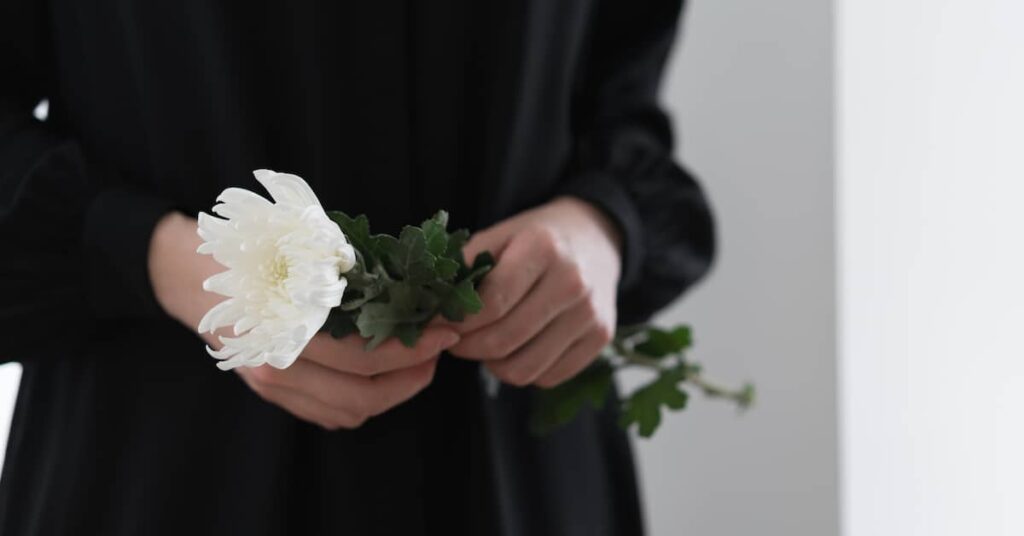 Woman in black holds white flower. | Maggiano, DiGirolamo & Lizzi