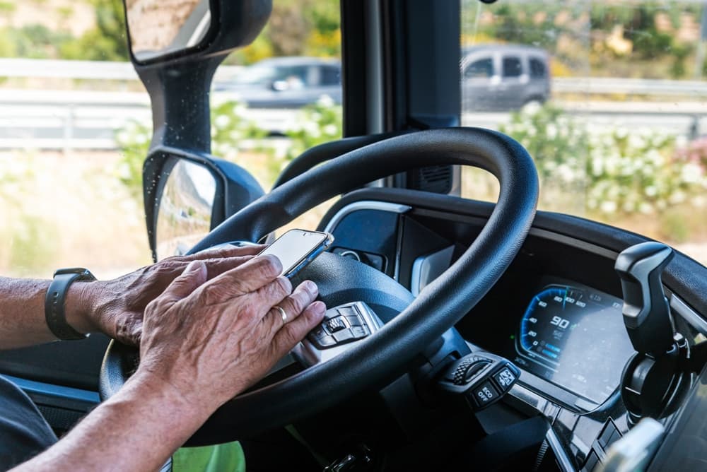 Senior truck driver’s hands texting on a mobile phone while driving