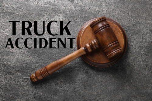 Wooden judge’s gavel resting on a dark stone surface with the words “Truck Accident” in bold black letters, representing legal action after a truck crash.