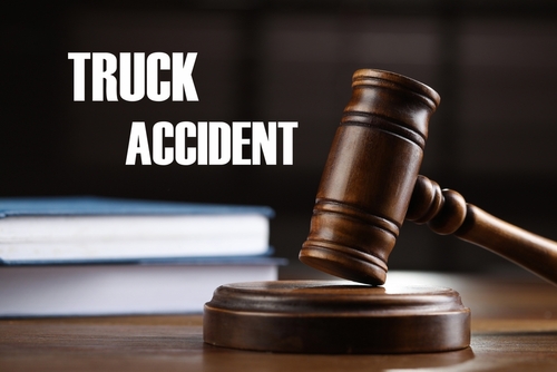 Wooden judge’s gavel resting on a sound block next to legal books with the words “TRUCK ACCIDENT” displayed in bold white letters in the background.