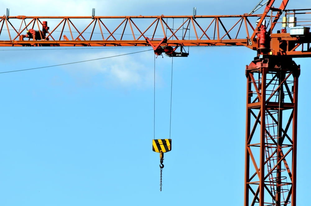Tower crane with suspended lifting hook used to move heavy materials at a construction site