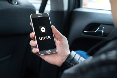 Uber customer sitting in the backseat of a car using smartphone app.