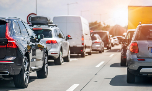 Traffic jam on a highway with various vehicles including SUVs and a white van visible in the lanes.