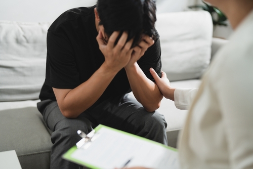 man with psychologist taking notes during therapy session.