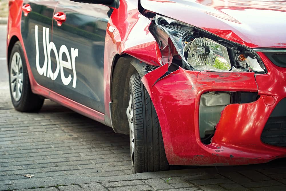 Uber rideshare vehicle with significant front-end damage after a motor vehicle collision.