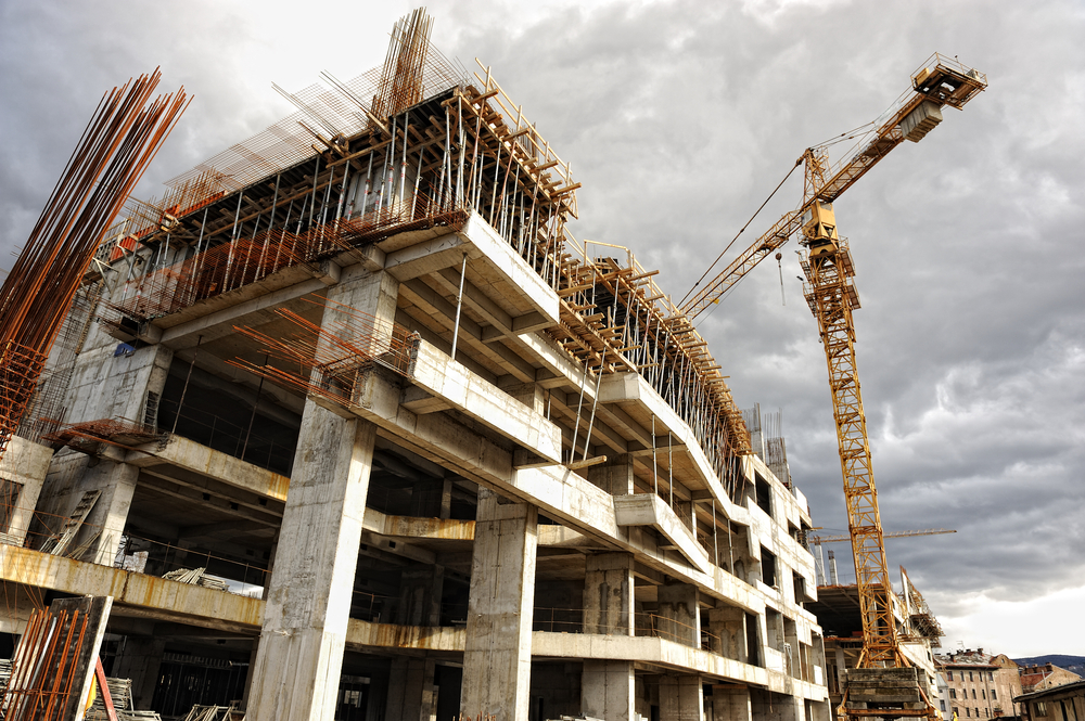 Construction site of a multi-level building with exposed concrete structures and a crane on the right side