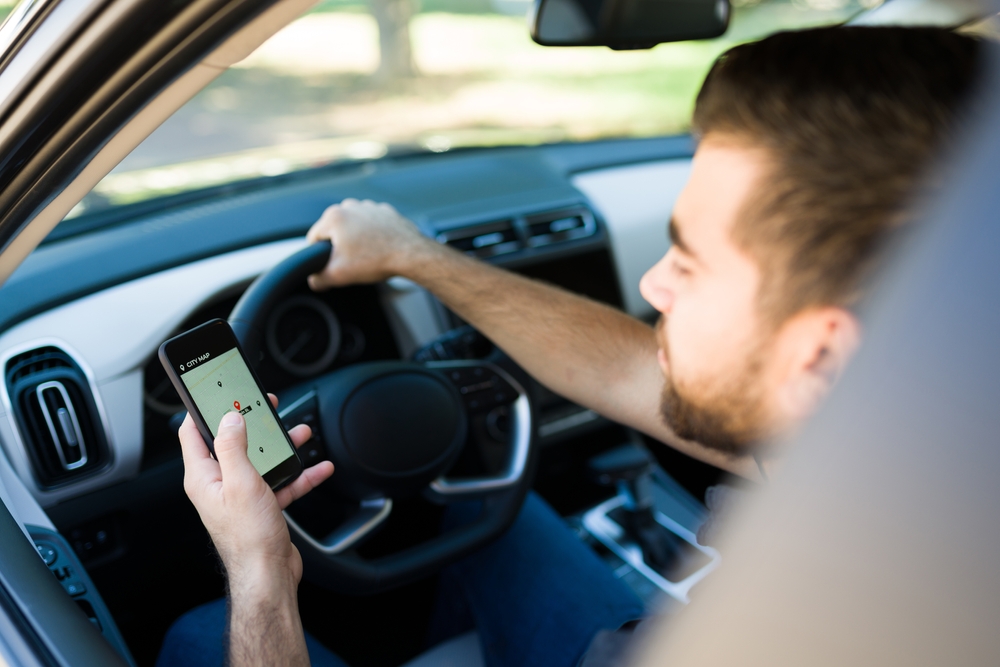 Rideshare driver viewing a GPS navigation app on a smartphone before starting a trip