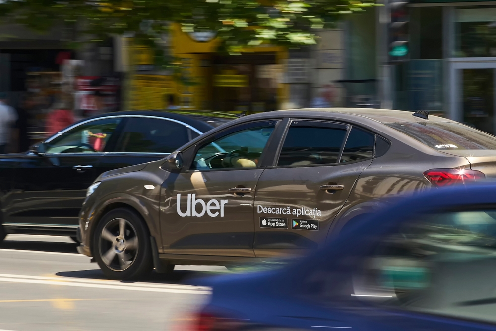 Uber-branded rideshare vehicle traveling along a busy city street.