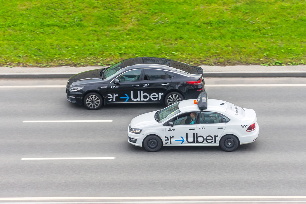 White and black passenger car Uber Taxi rides on the highway aerial view
