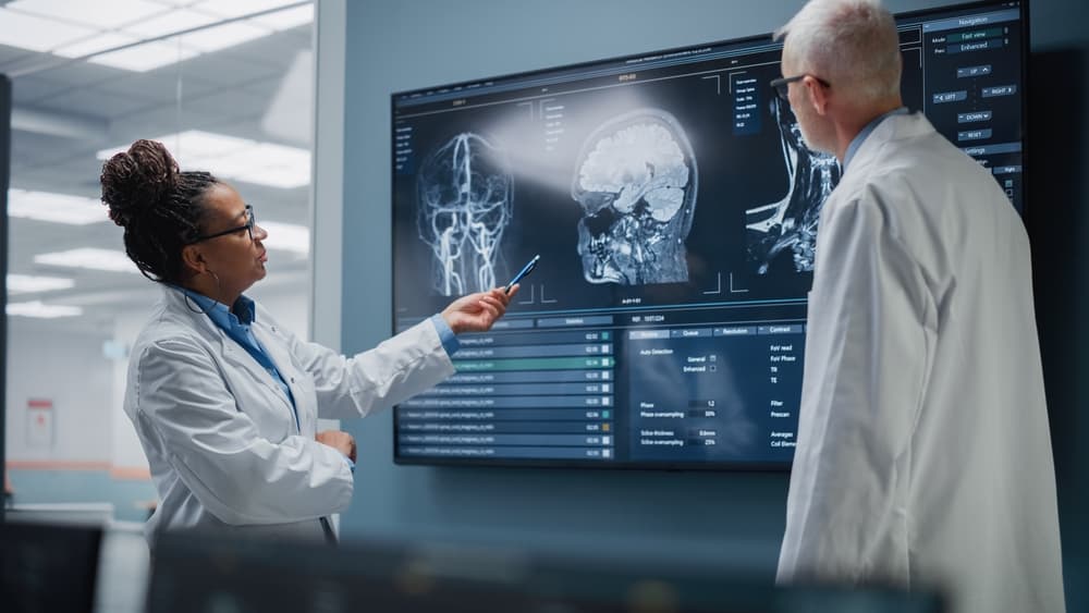 Two doctors reviewing a head scan on a computer monitor in a medical office.